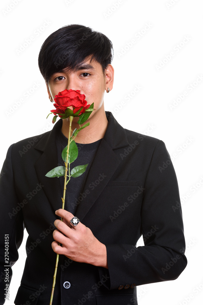 Studio shot of cool handsome Asian man smelling red roses Studio shot of cool handsome Asian man smelling red roses