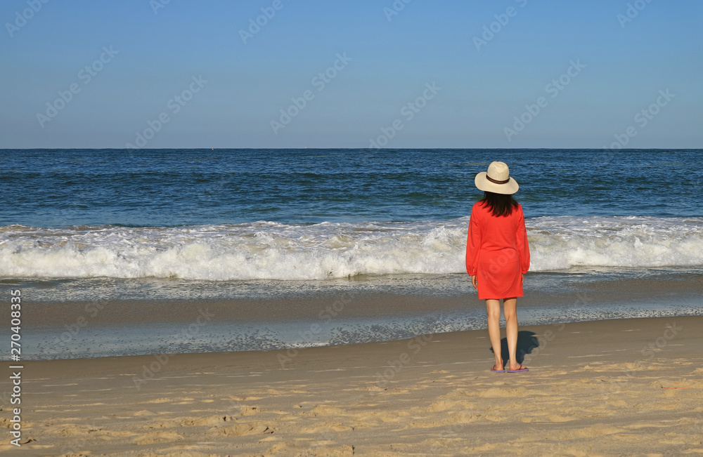 Young woman looking at the splashing wave on the beach Young woman looking at the splashing wave on the beach