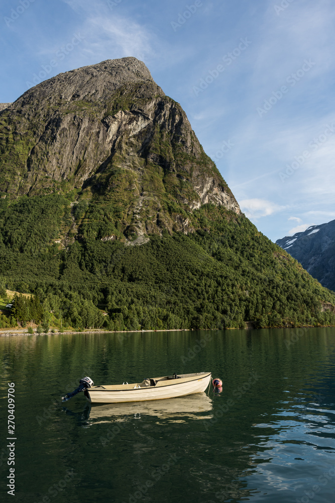 A boat on a lake, near the mountains. A boat on Oppstrynsvatnet lake, in Norway. Vertical layout