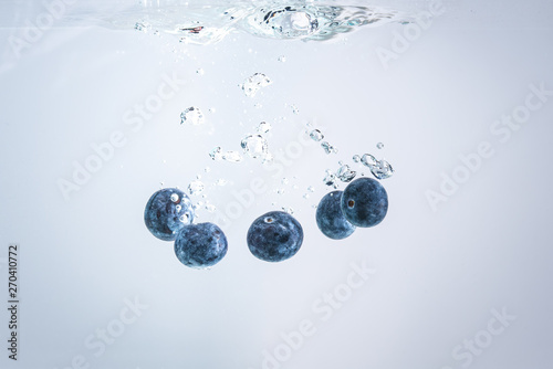 Organic Blueberries dropped into clear water.