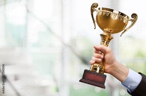 Hand holding golden trophy on blurred background