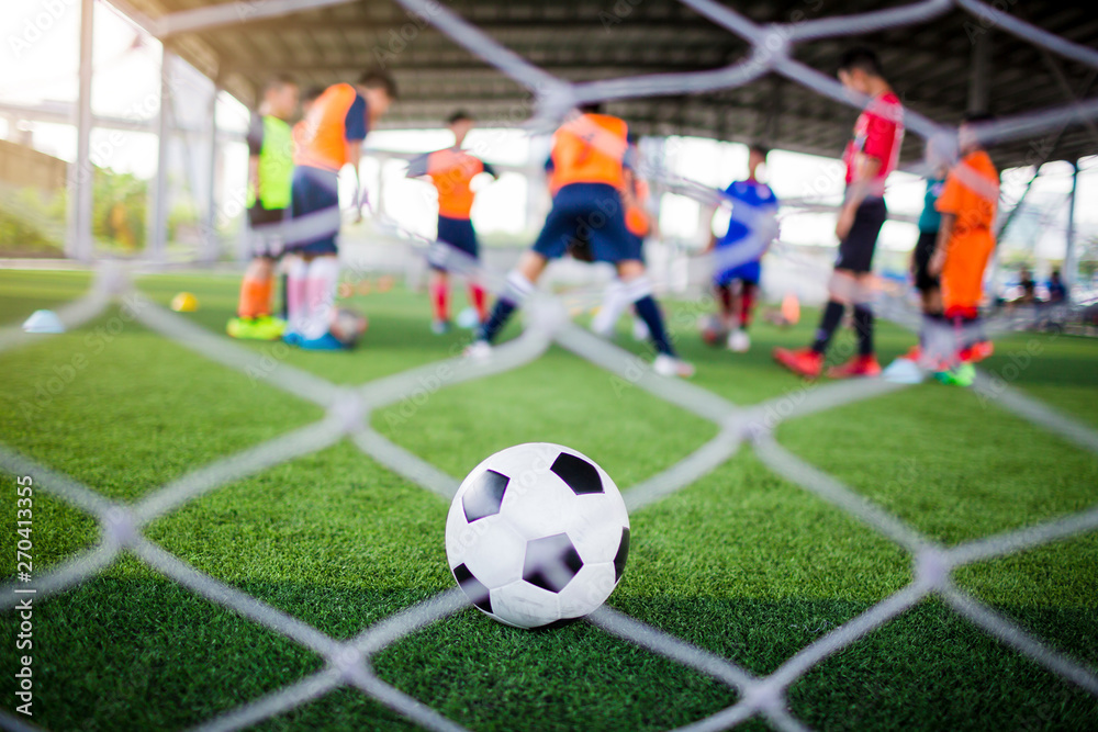 selective focus to football is in goal with blurry white mesh goal