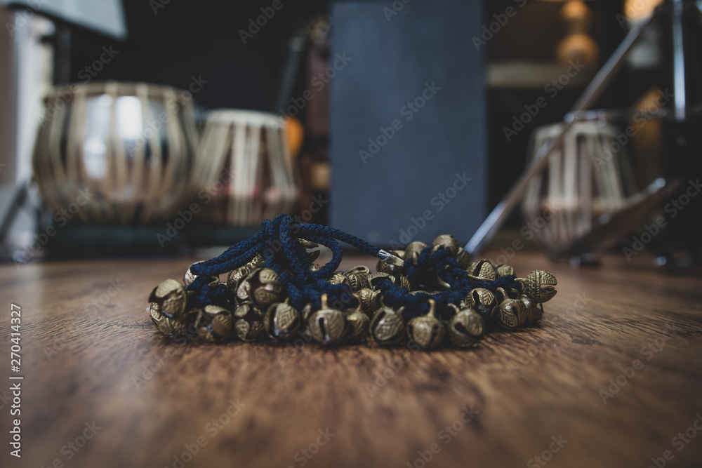 Tabla and ghungroo - Indian drums and dance cymbals on a wooden floor - background of musical instruments - with copy space. 