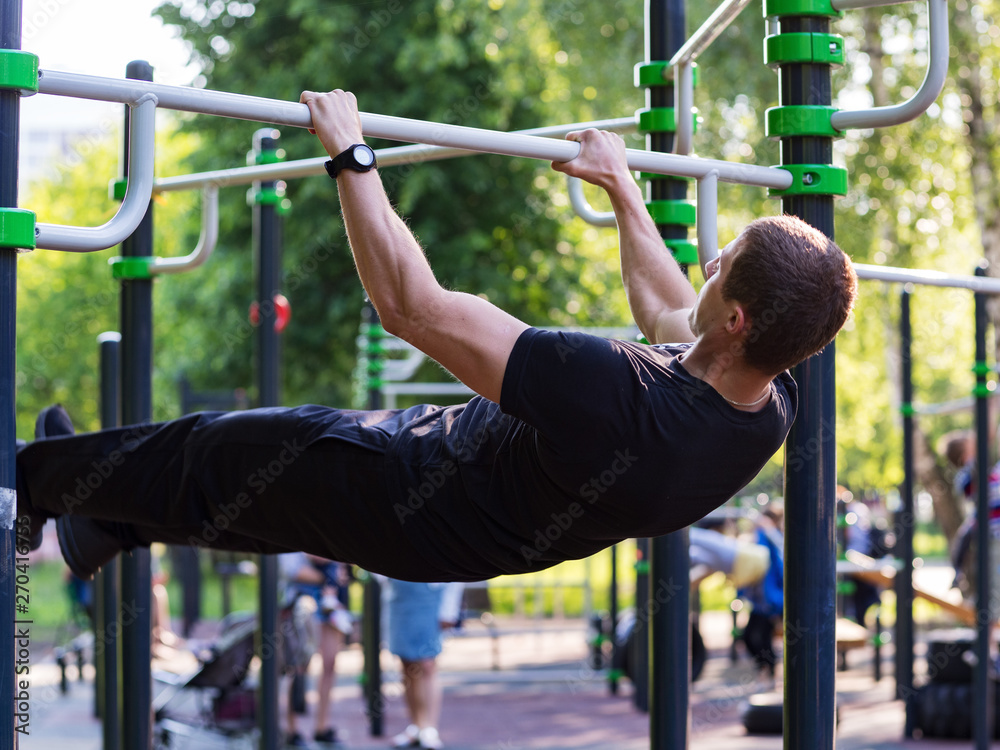 Fototapeta premium Male athlete performs exercises on the bar