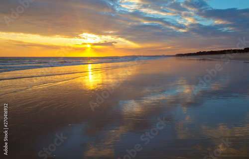 Beautiful south sunset on the sea. Deserted sandy shore of the Atlantic Ocean with the reflection of the clouds. Seascape. Natural summer background. Vilamoura  Falesia  Algarve  Portugal