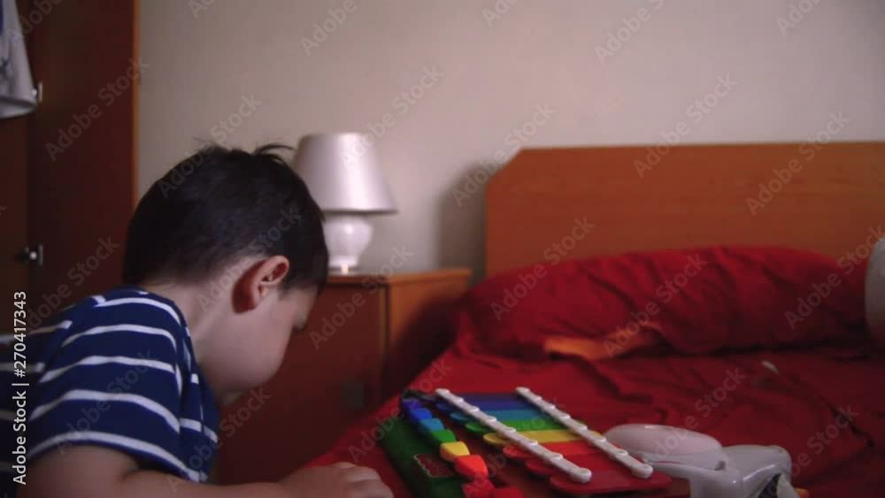 Cute two years old boy playing xylophone in the bedroom Cute two years old boy playing xylophone in the bedroom