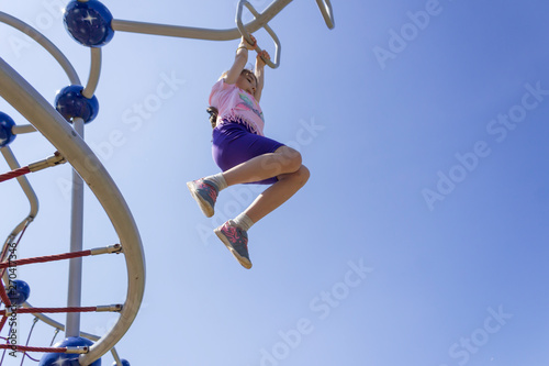 teenage girl playing with motor activity developer toys like rope wall and spider web at the playground
