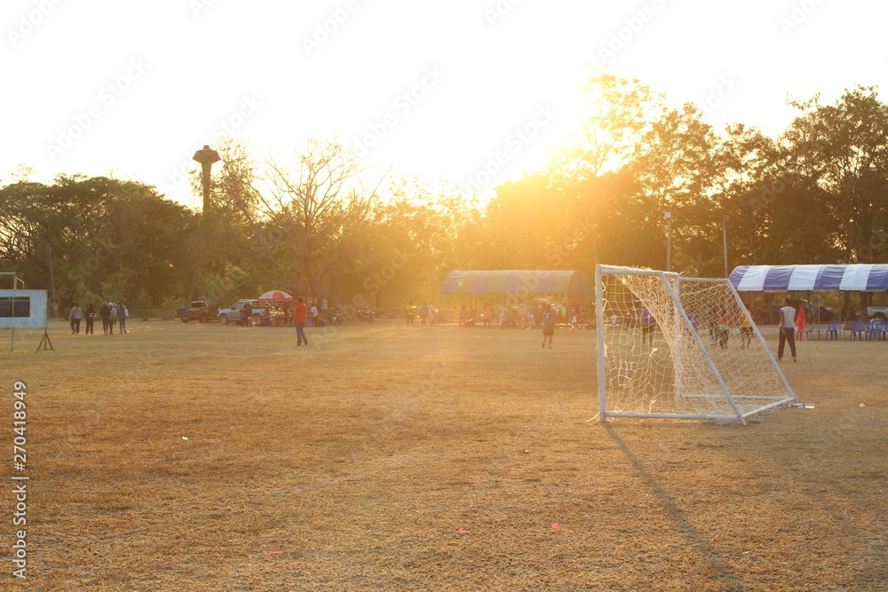 People are walking on the football field with golden yellow sunshine in the evening filmed blurred People are walking on the football field with golden yellow sunshine in the evening filmed blurred