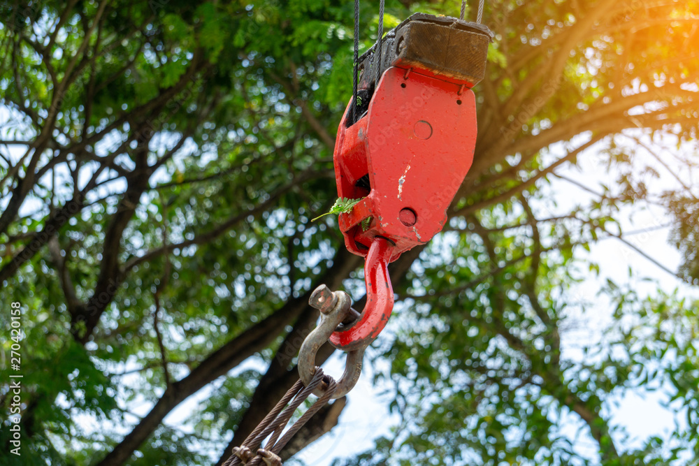 Mobile construction cranes with red lifting steel crane hook, swivel joint and connection steel sling. Blurred beautiful tree background. Building and construction equipment. Mobile construction cranes with red lifting steel crane hook, swivel joint and connection steel sling. Blurred beautiful tree background. Building and construction equipment.