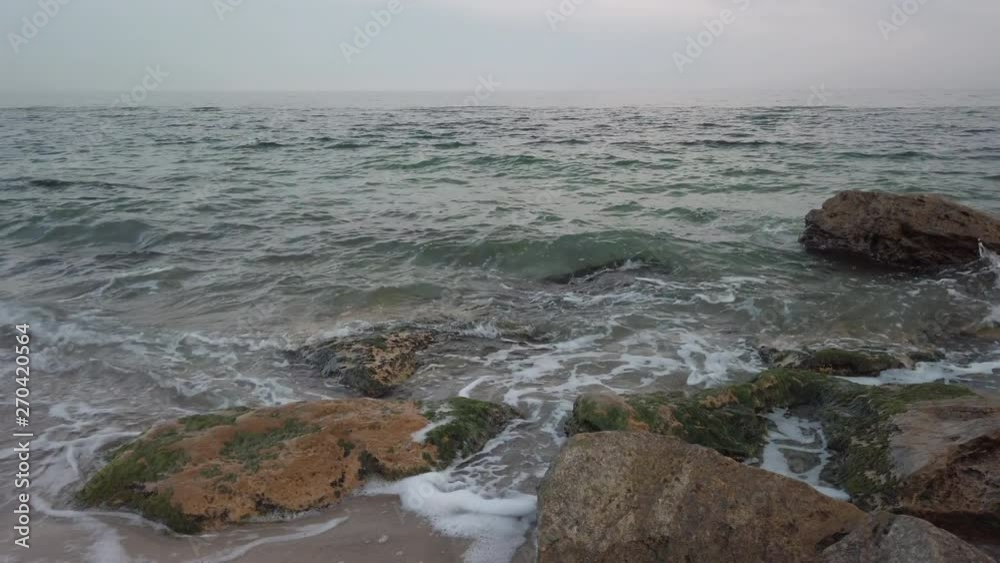 Rocks and water on Arcadia beach in Odessa, Ukraine on April 8, 2019. Early evening. Medium shot, pan.