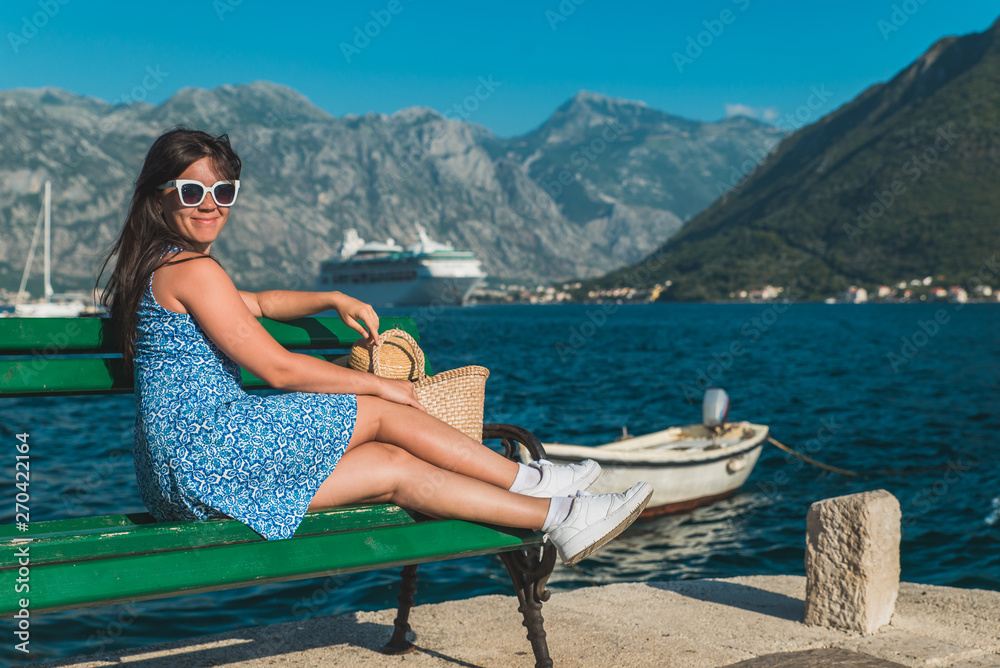 beautiful woman on bench sea and mountains on background. cruise liner