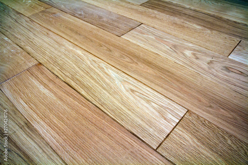 Natural light brown wooden parquet floor boards. Sunny soft yellow texture, copy space perspective background.