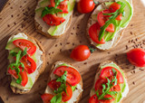 Fresh  toasts with avocado and tomatoes on wooden table 