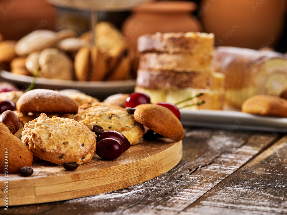 Oatmeal cookies and sand chocolate cake with cherry berry and crispy wafer rolls with cream on cutting board on wooden table in rustic style. Limitations for diabetics. Rejection of many products. Oatmeal cookies and sand chocolate cake with cherry berry and crispy wafer rolls with cream on cutting board on wooden table in rustic style. Limitations for diabetics. Rejection of many products.