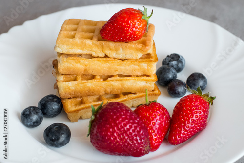  Belgian waffles with Strawberry and Blueberries on white blate close up