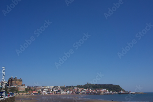 View along beachfront towards castle and harbour in Scarborough, Yorkshire, UK on a clear bright sunny blue sky day