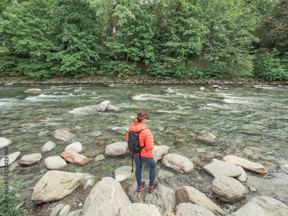 unrecognizable person looking from the rocks to a rushing river surrounded by vegetation unrecognizable person looking from the rocks to a rushing river surrounded by vegetation