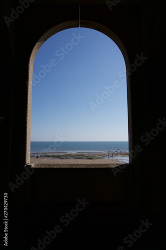 Looking out to sea through archway across empty sandy beach in Scarborough  Yorkshire  UK on a bright blue sky sunny day