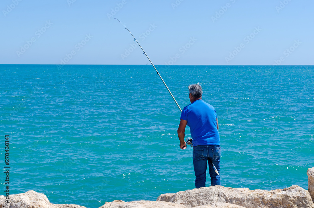fisherman using a fishing rod for recreational fishing fisherman using a fishing rod for recreational fishing