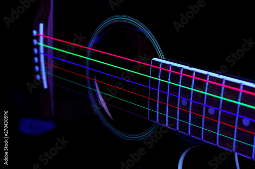 Acoustic guitar with colored luminous strings. On a black background