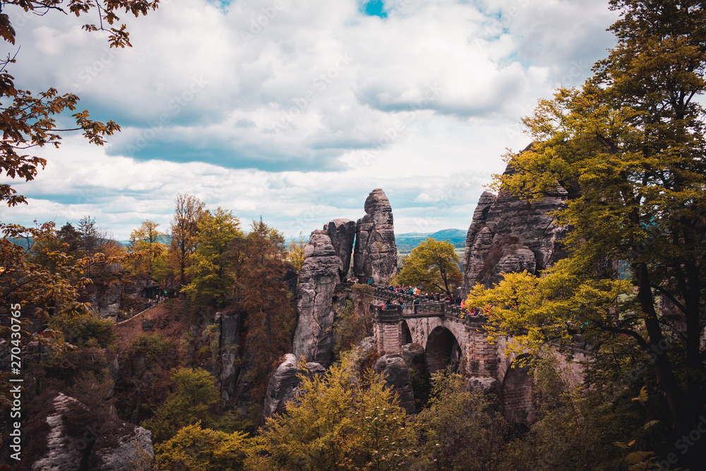 Bastei Bridge in Saxon Switzerland National Park, Germany. Sandstone mountains. Landmark of Saxonia. Cloudy spring or summer day. Colored trees and leafs.