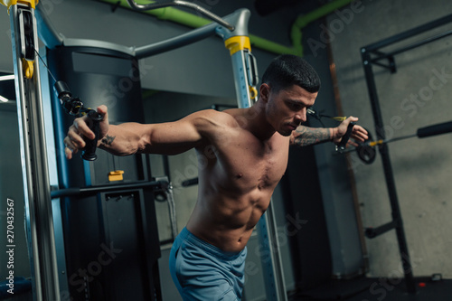 Tableau sur toile Young strong man in gym doing chest cable workout