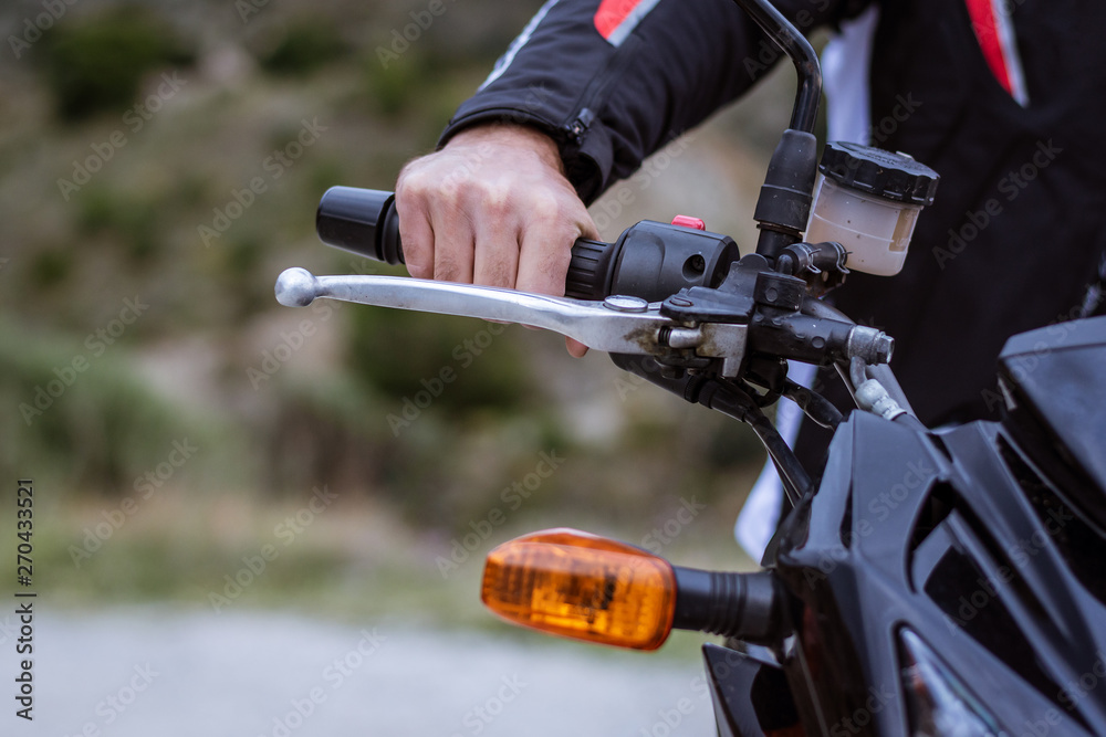 Detail of the handlebar of a motorbike with the brake and the pilot's hand Detail of the handlebar of a motorbike with the brake and the pilot's hand