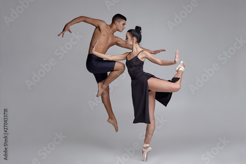 Φωτογραφία Two athletic modern ballet dancers are posing against a gray studio background
