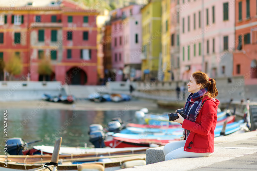 Young female tourist enjoying the view of Vernazza, one of the five centuries-old villages of Cinque Terre, located on rugged northwest coast of Italian Riviera, Italy. Young female tourist enjoying the view of Vernazza, one of the five centuries-old villages of Cinque Terre, located on rugged northwest coast of Italian Riviera, Italy.