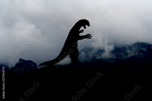 Fototapeta Naklejka Na Ścianę i Meble -  Godzilla-artiges Monster als schwarze Silhouette auf einem Berg
