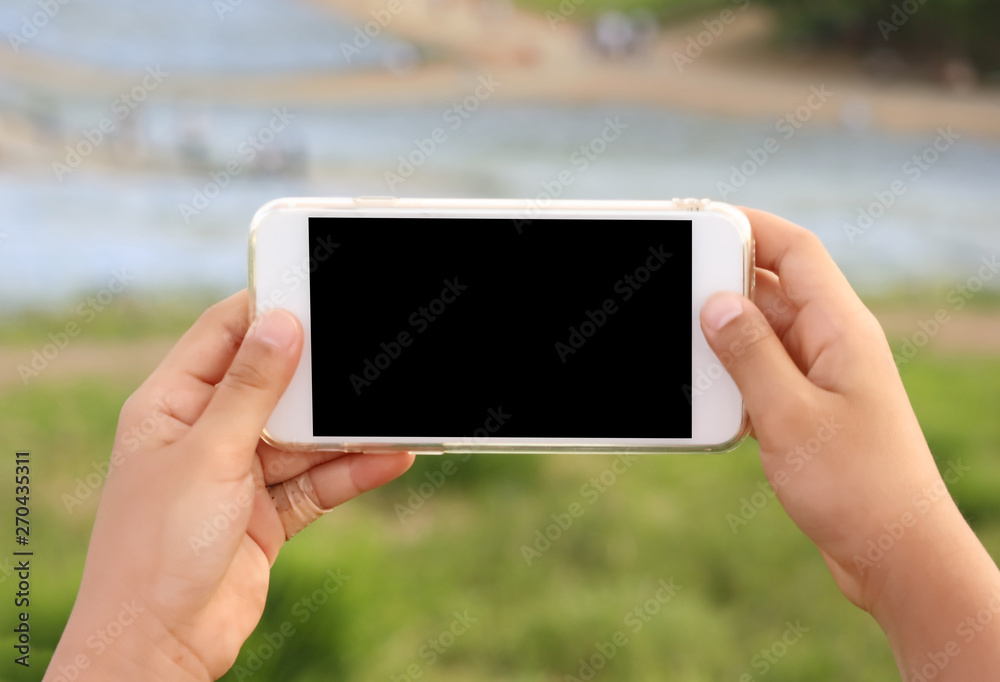 A gril hands holding empty black touchscreen smart phone at outdoor park.