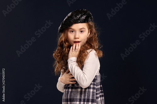 Stylish brunette kid is posing in studio on a black background. Children's fashion. photo