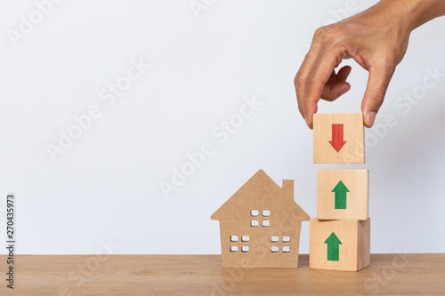 Canvas Print Hand arranging wooden cube stack with arrow pointing up and arrows down, house model on white background