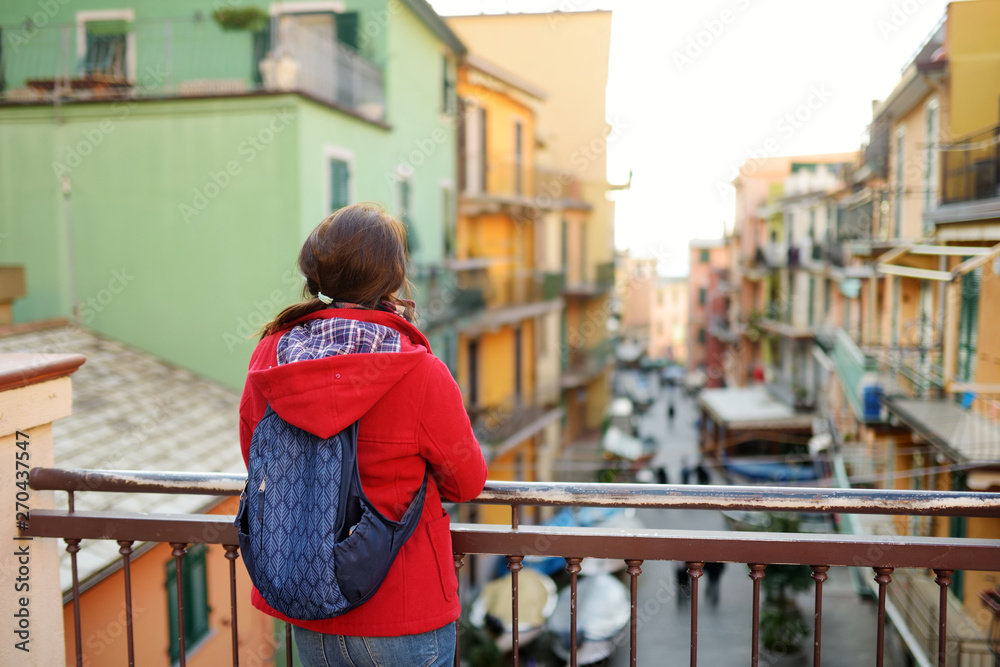 Young female tourist enjoying the view of Manarola, one of the five centuries-old villages of Cinque Terre, located on rugged northwest coast of Italian Riviera, Italy. Young female tourist enjoying the view of Manarola, one of the five centuries-old villages of Cinque Terre, located on rugged northwest coast of Italian Riviera, Italy.