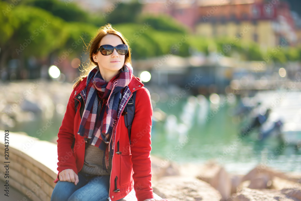 Young female tourist enjoying the view of small yachts and fishing boats in marina of Lerici town, located in the province of La Spezia in Liguria, Italy. Young female tourist enjoying the view of small yachts and fishing boats in marina of Lerici town, located in the province of La Spezia in Liguria, Italy.