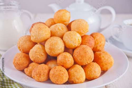 Small balls of freshly baked homemade cottage cheese doughnuts in a plate on a white background.
