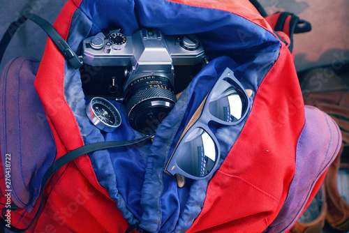 Closeup sunglasses and compass and camara in the backpack.
