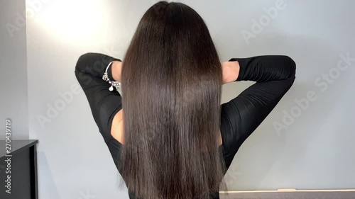 Brunette woman waving her beautiful, healthy hair after a treatment in a beauty salon.Slow motion