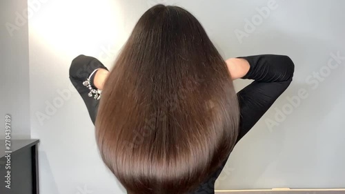 Brunette woman waving her beautiful, healthy hair after a treatment in a beauty salon.Slow motion