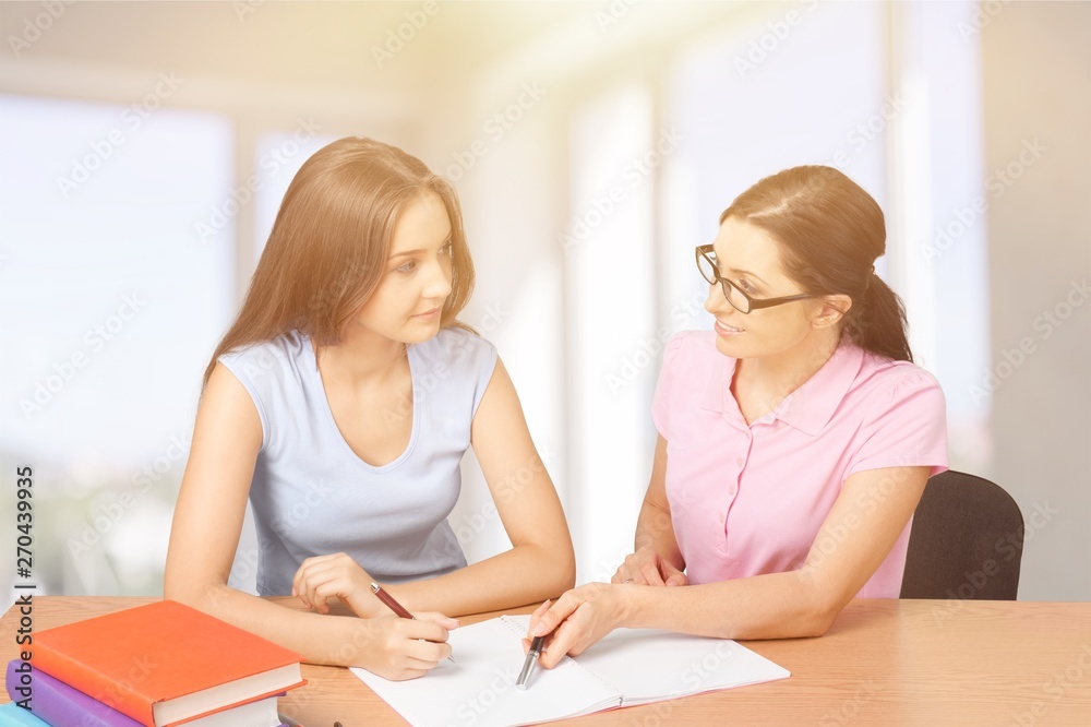 Mother helping happy daughter with homework on background Mother helping happy daughter with homework on background