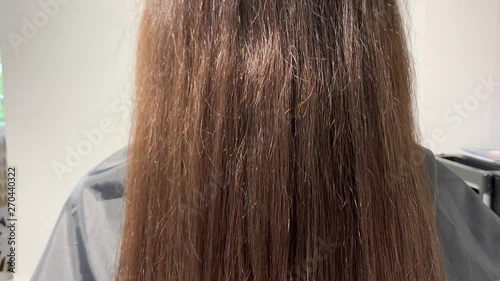 Brunette woman waving her beautiful, healthy hair after a treatment in a beauty salon.Slow motion