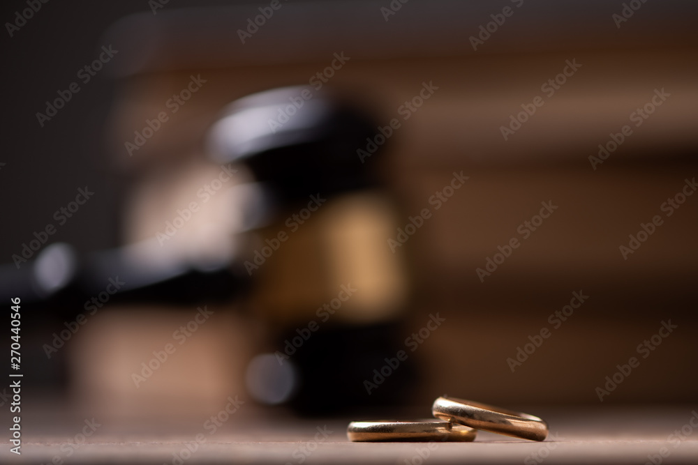 Judge gavel with wedding rings on wooden table