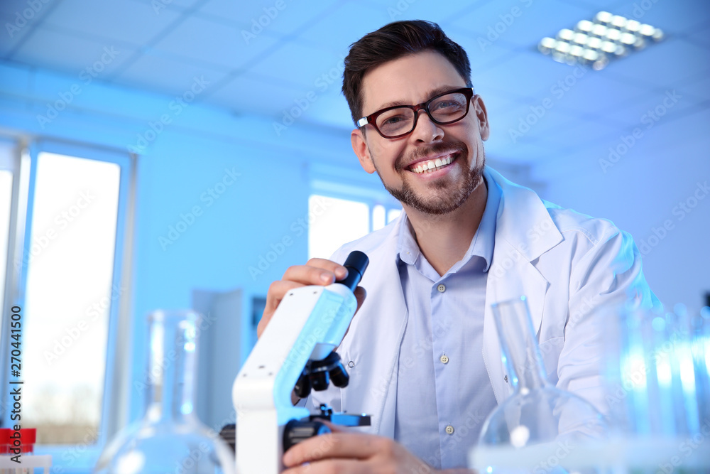 Male scientist with modern microscope in chemistry laboratory, space for text Male scientist with modern microscope in chemistry laboratory, space for text