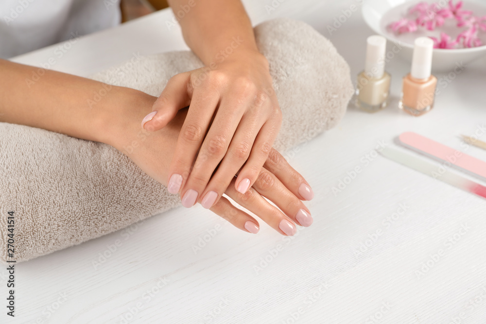 Woman showing neat manicure at table, closeup with space for text. Spa treatment