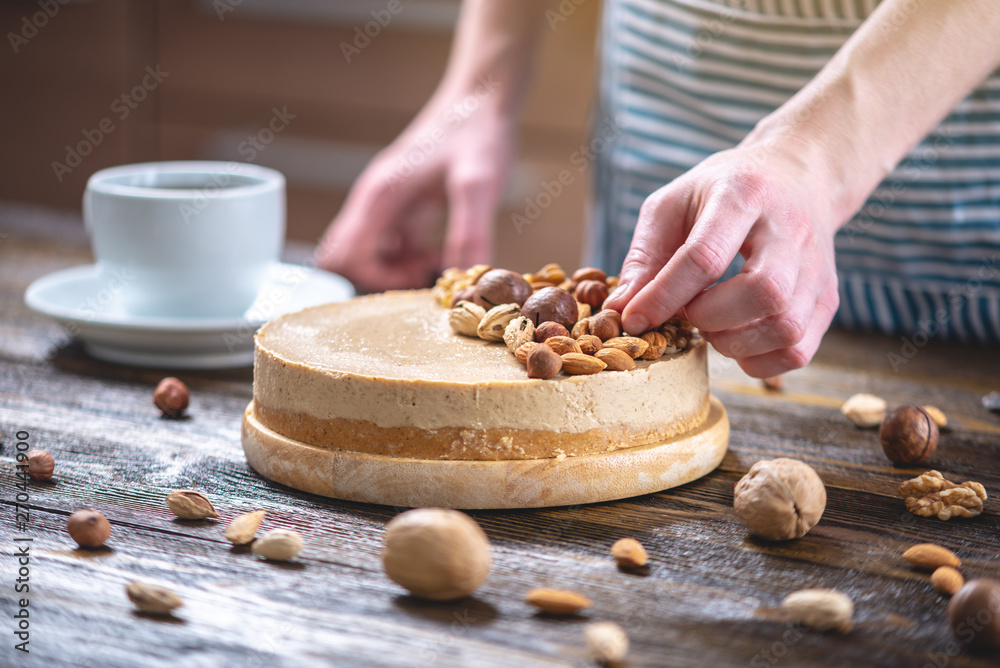 Raw nutty cake decorated with walnut, almond, hazelnut on a dark wooden background. Gluten free and sugar free food