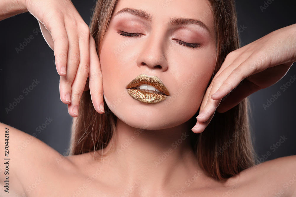 Fototapeta premium Woman with gold lipstick on grey background, closeup