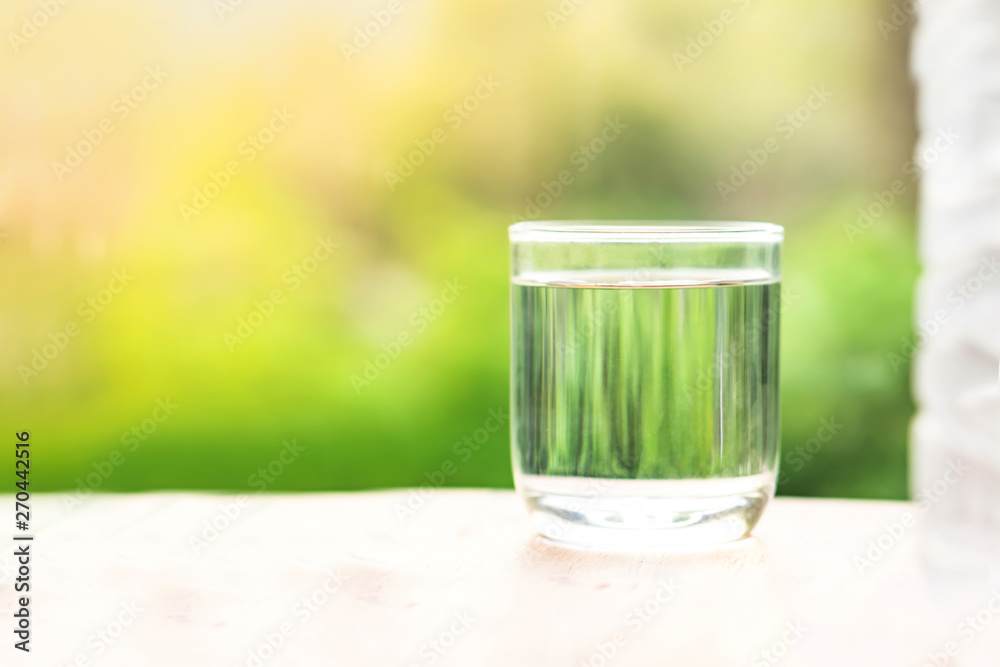 glass of clean and fresh water on wooden table with nature background glass of clean and fresh water on wooden table with nature background