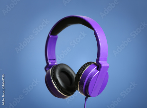 Stylish headphones with pads on color background