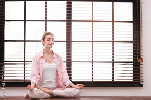 Fototapeta Naklejka Na Ścianę i Meble -  Young woman meditating at home, space for text. Zen concept