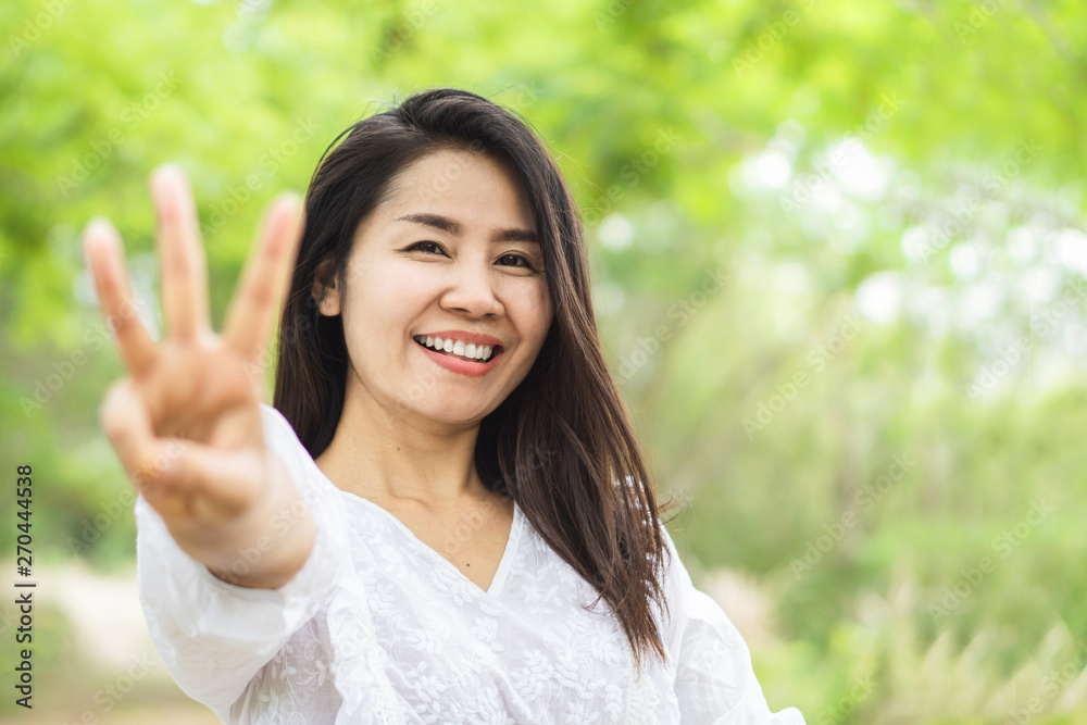 Happy Asian woman showing finger age 30 years old and smiling to camera in a park 